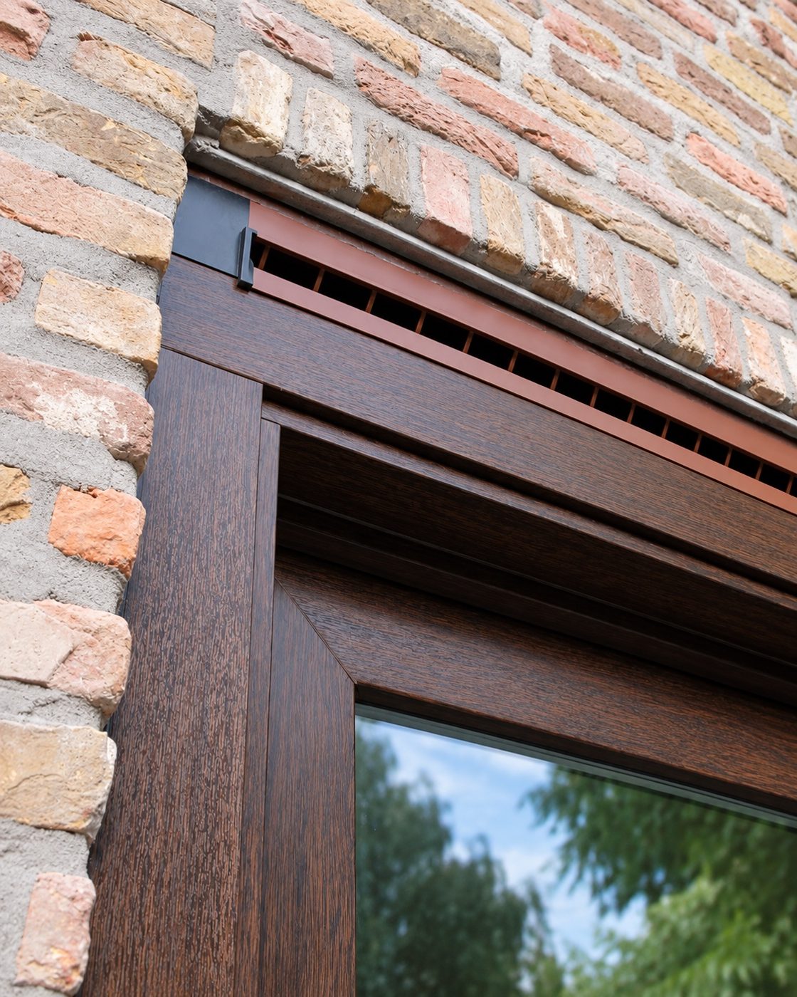 Hoekdetail van een bruin aluminium kozijn in metselwerk
